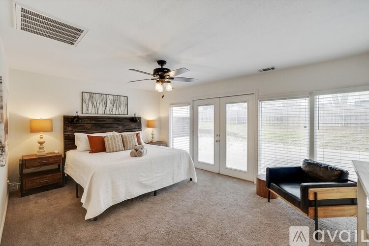 A bedroom with a large bed, a ceiling fan, and a sliding glass door.