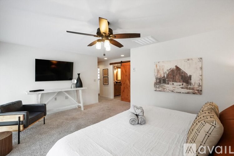 A bedroom with a bed, a couch, a television, and a painting on the wall.