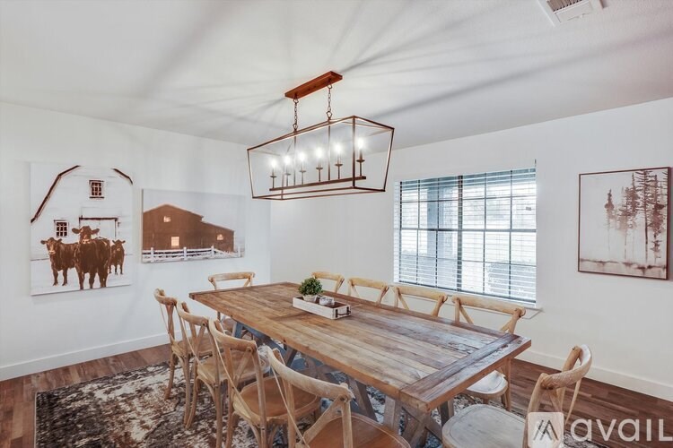 A room with a wooden table and chairs, a hanging light fixture, and pictures on the wall.