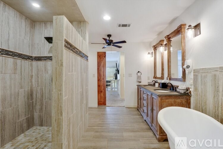 A bathroom with a tub, sink, and mirror.