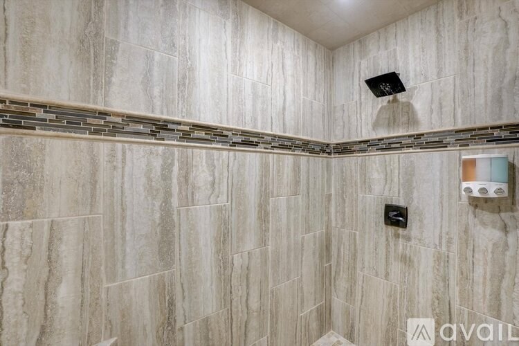 A bathroom with a tiled wall and a shower.