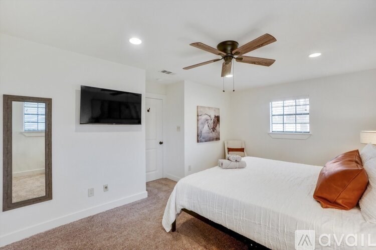A bedroom with a bed, a ceiling fan, and a television.