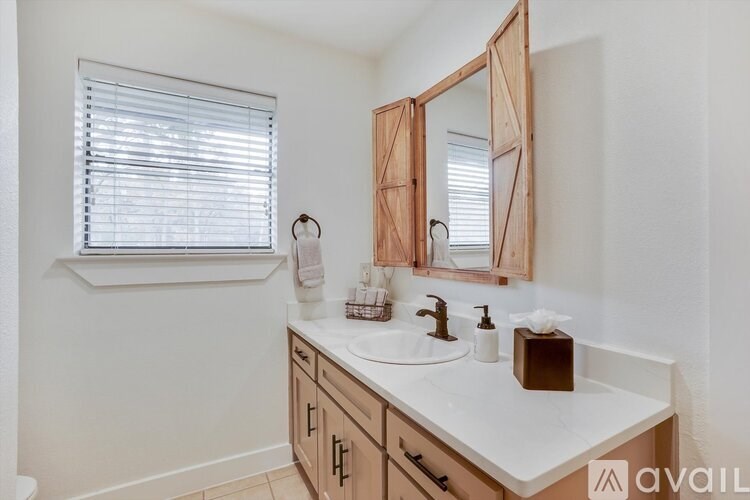 A bathroom with a white countertop and a wooden medicine cabinet.