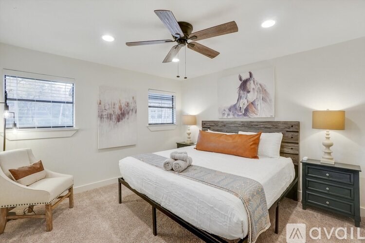 A bedroom with a bed, chair, and artwork on the wall.