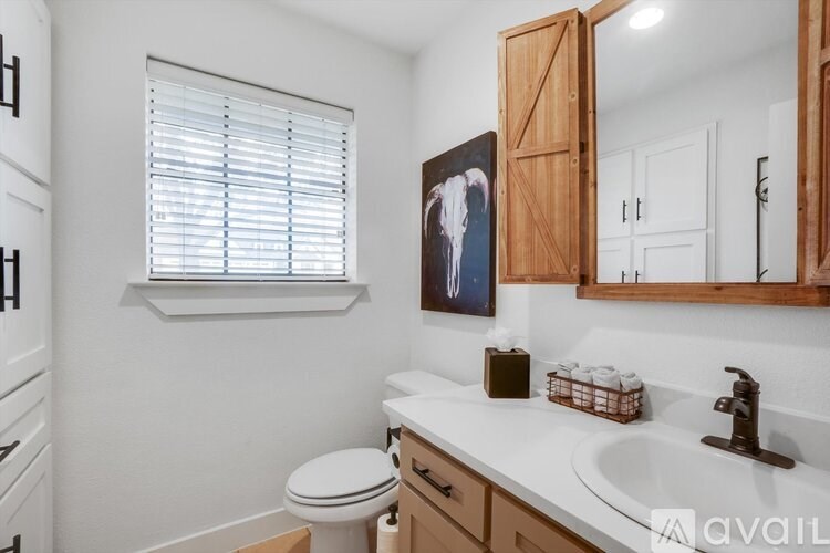 A bathroom with a toilet, sink, and a painting of a cowboy on the wall.
