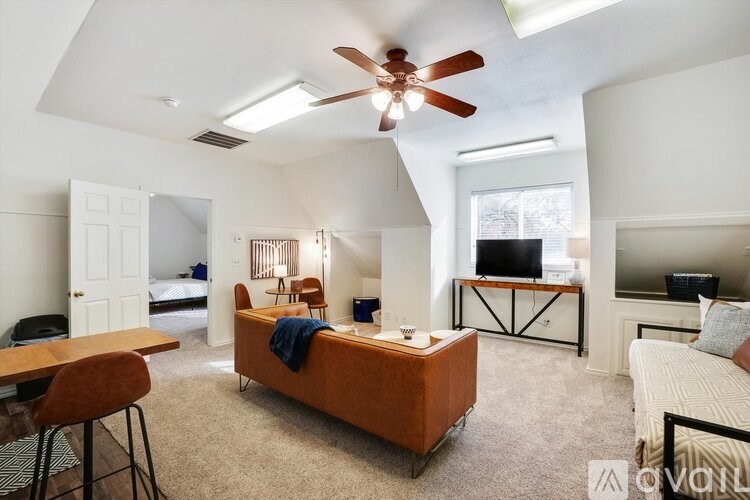 A bedroom with a bed, a desk, and a ceiling fan.