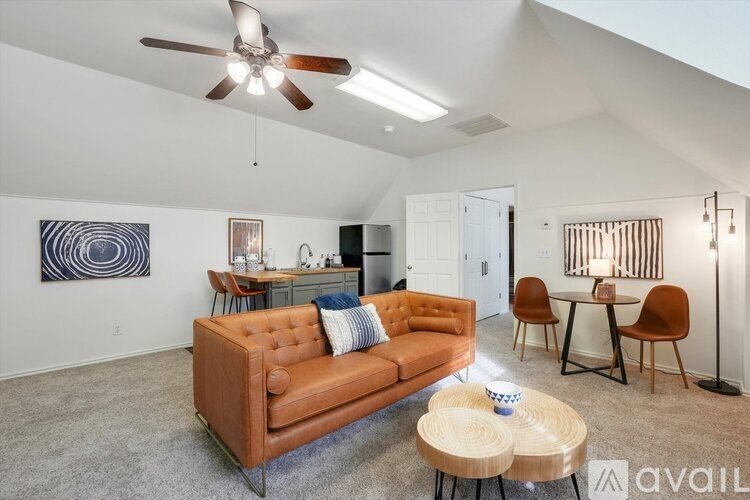 A living room with a brown couch, a ceiling fan, and a dining table with chairs.