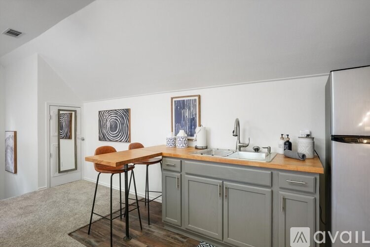 A kitchen with a wooden table and chairs, a sink, and a refrigerator.