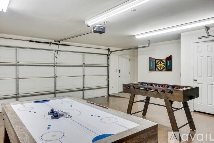 A foosball table is in a garage with a dart board on the wall.