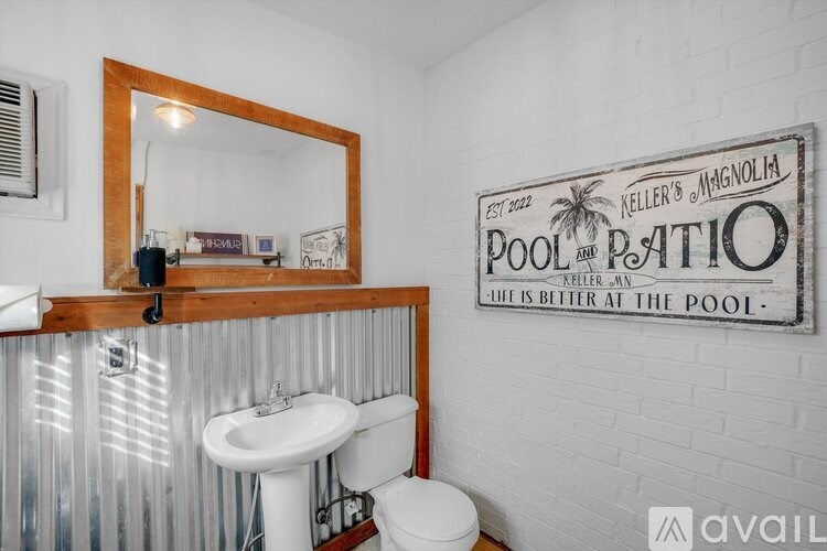 A bathroom with a mirror, sink, toilet and a sign on the wall.