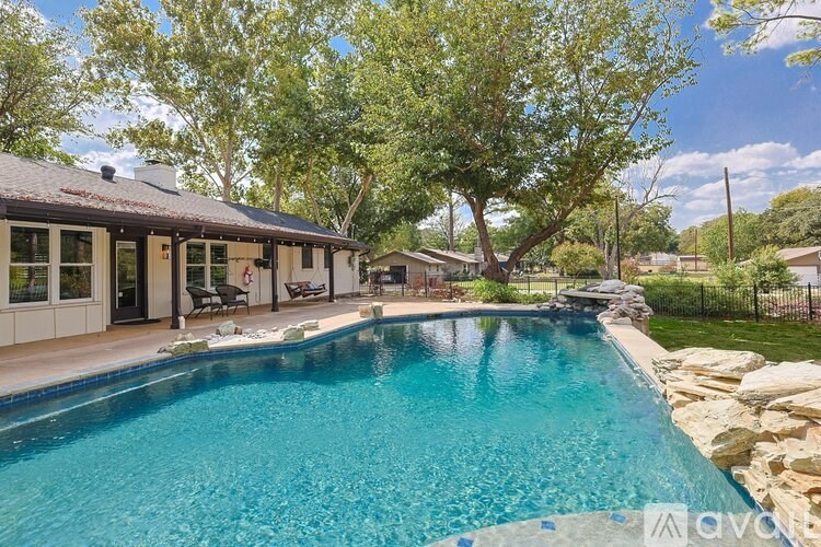 A swimming pool in a backyard with a house and trees in the background.
