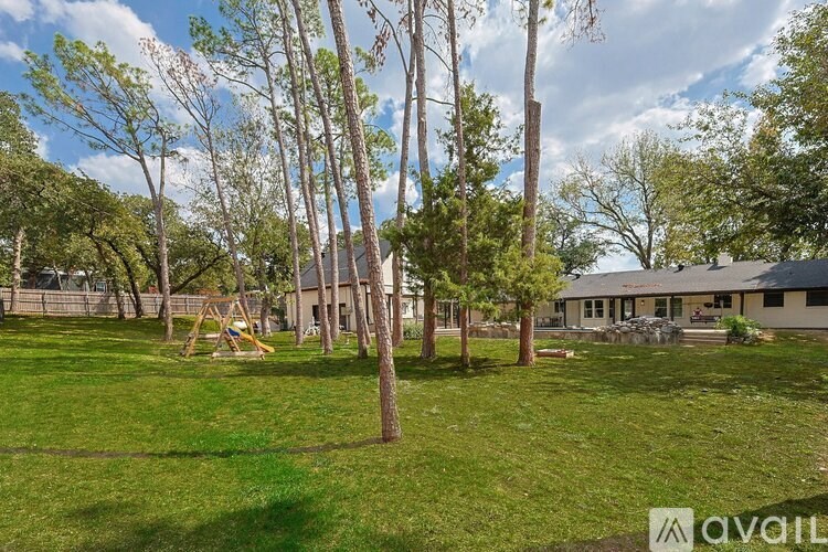 A playground with swings and slides is surrounded by tall trees.