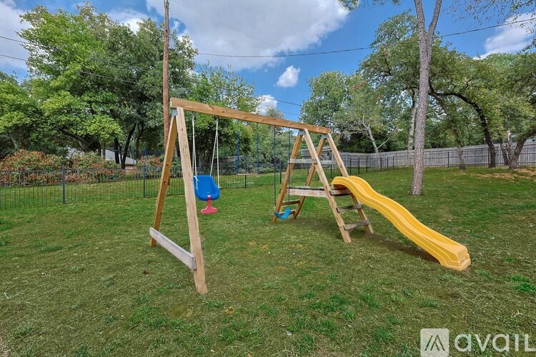 A wooden swing set with a yellow slide in a grassy backyard.