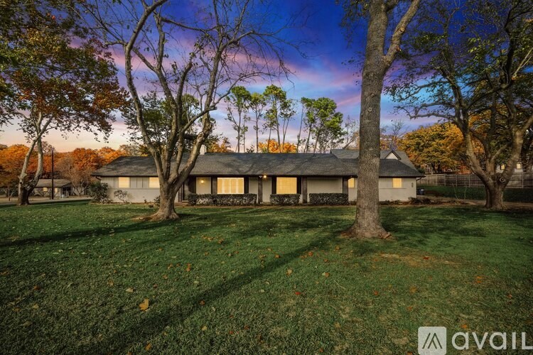 A house with a lawn and trees in front of it.