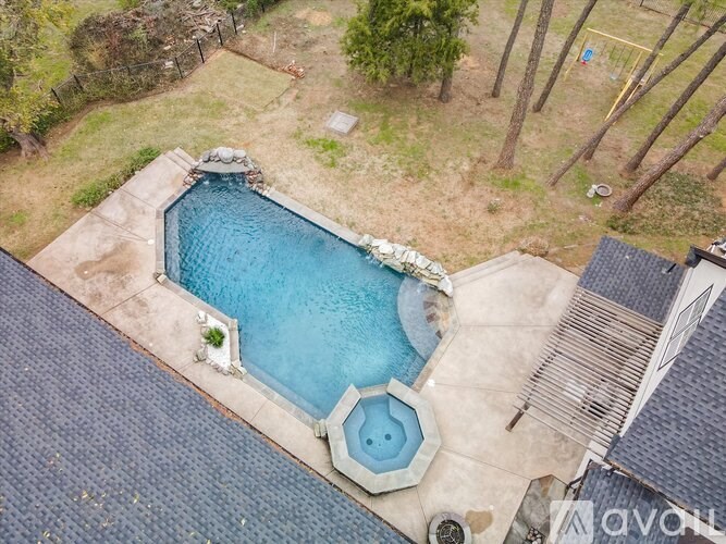 A swimming pool surrounded by a concrete patio and a stone border.