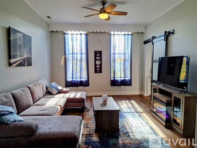 A living room with a brown couch and a ceiling fan.