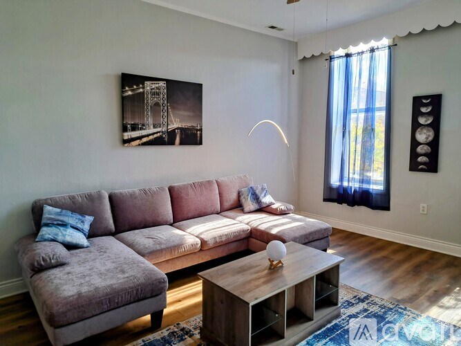 A living room with a grey couch, a coffee table, and a painting on the wall.