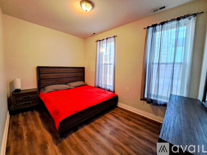A bedroom with a large bed and wooden floors.