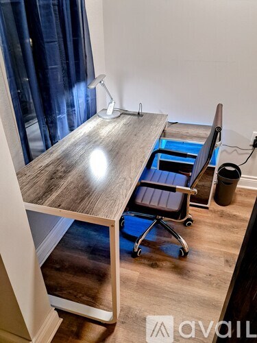 A wooden desk with a chair and a lamp on it.