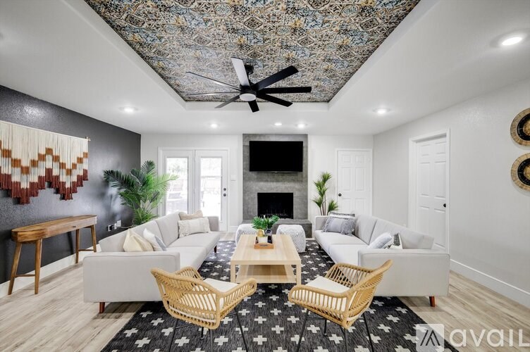 A living room with a white couch, a wooden coffee table, and a patterned ceiling.