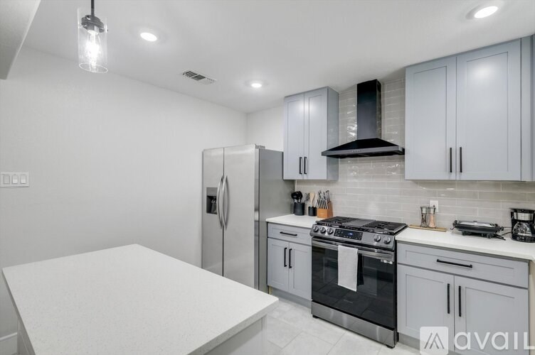 A kitchen with a white table and stainless steel appliances.