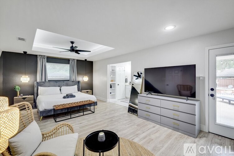 A modern bedroom with a large bed, a television, and a balcony.