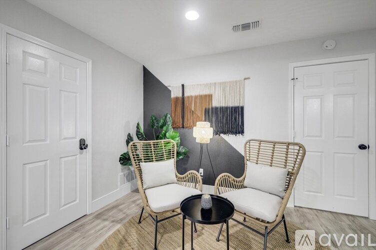 A living room with a black table and two white chairs.