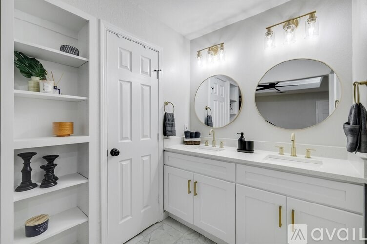 A bathroom with a white door, a white sink, and a white shelf with decorative items.