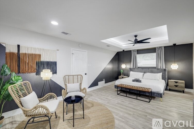 A bedroom with a bed, two chairs, and a ceiling fan.