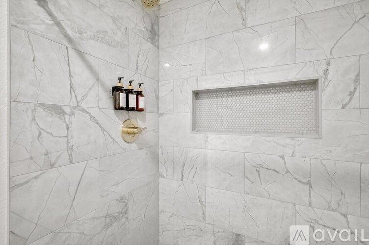 A bathroom with marble walls and a shower.