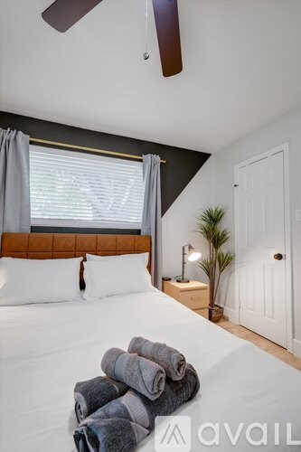A bedroom with a bed, a ceiling fan, and a window with curtains.