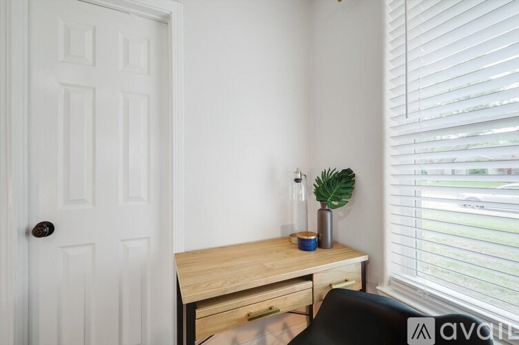 A white door is on the left of a desk with a plant on it.
