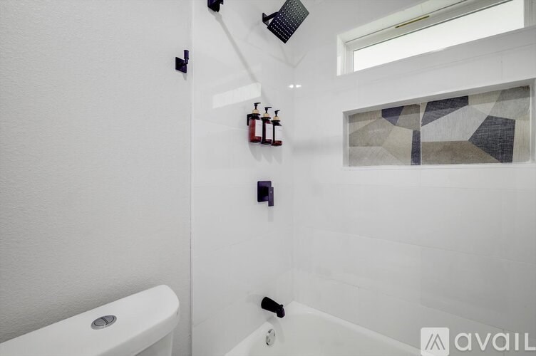 A white bathroom with a tub and a window.