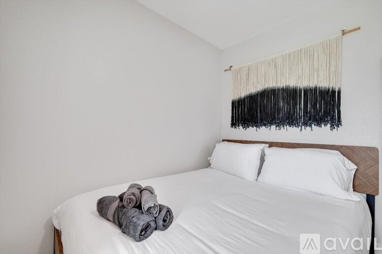 A bed with white sheets and a white pillow with a towel on top of it.