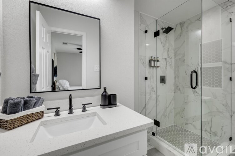 A bathroom with a marble shower and a white sink.