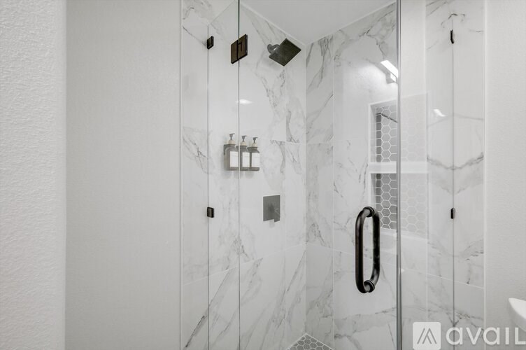 A white marble bathroom with a glass shower door.