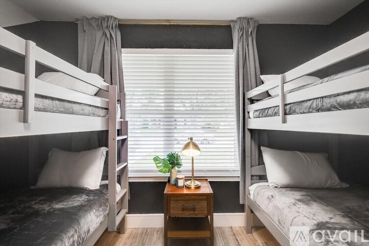 A room with two bunk beds and a small table with a lamp on it.