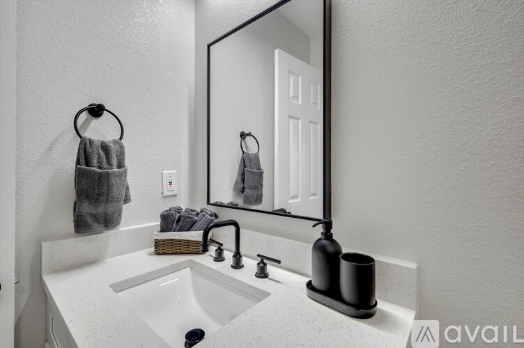 A bathroom with a sink, mirror, and towel.