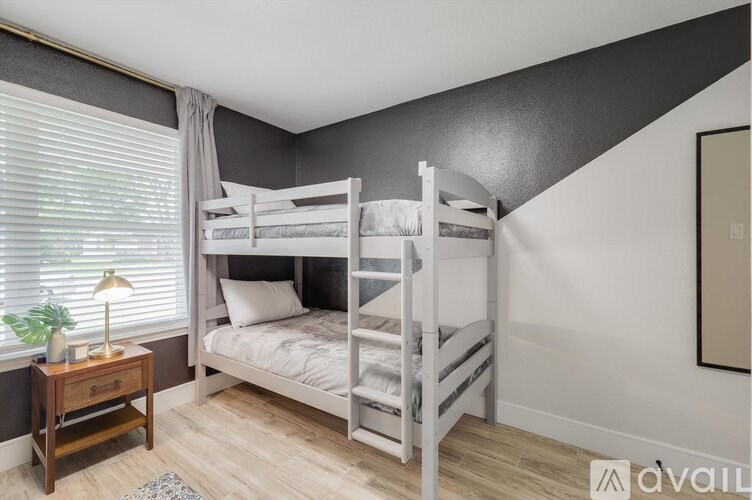 A bedroom with a bunk bed and a nightstand with a lamp.