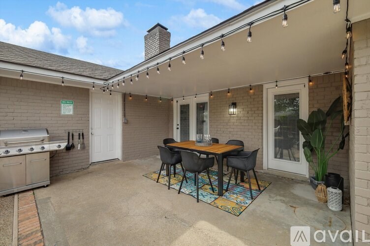 A patio with a table and chairs is covered with lights.