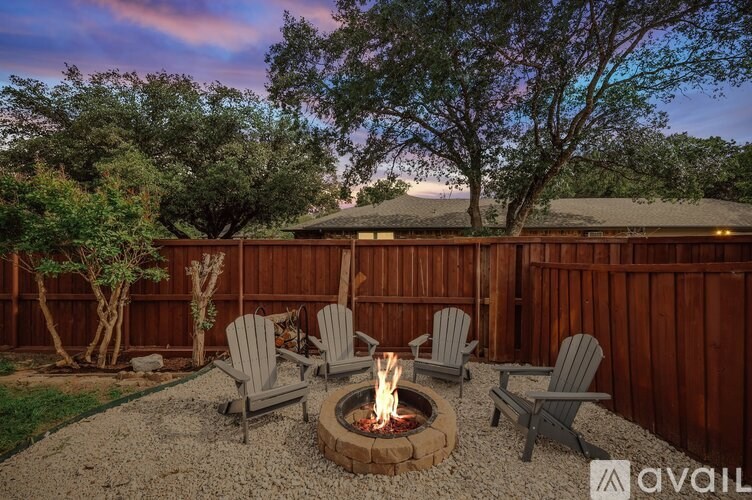 A backyard with a fire pit and chairs.