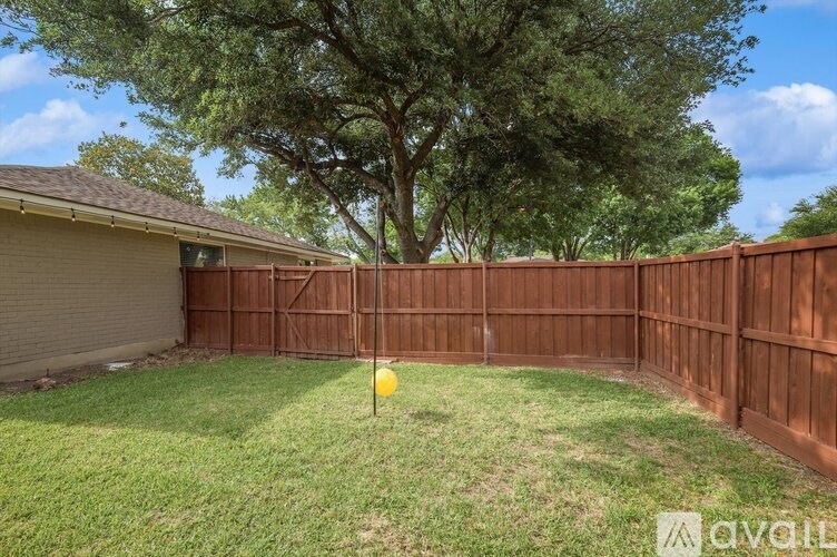 A backyard with a brown fence and a yellow flag on the grass.