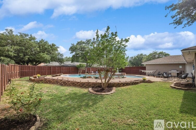 A backyard with a pool and a tree in the middle.