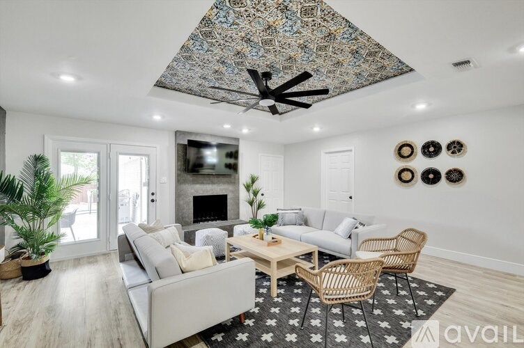 A living room with a grey couch, a wooden coffee table, and a ceiling fan with a blue and black patterned cover.