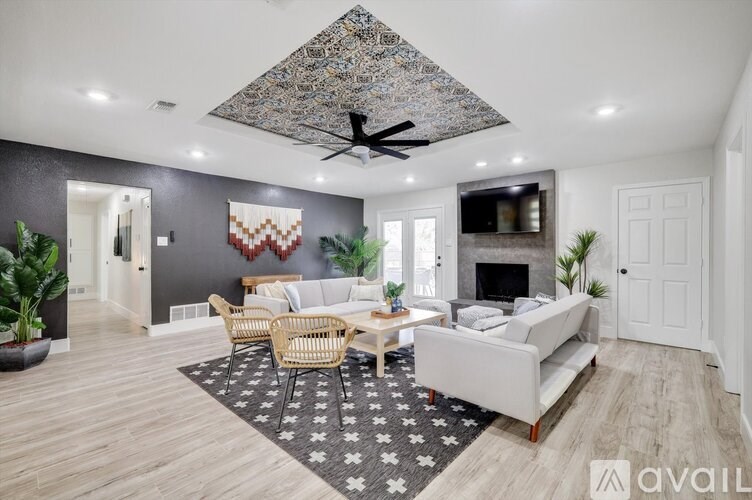 A living room with a large rug, a sofa, a chair, and a ceiling fan.