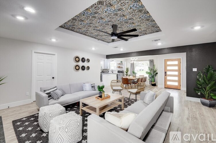 A living room with a grey couch, a wooden coffee table, and a ceiling fan with a mosaic design.