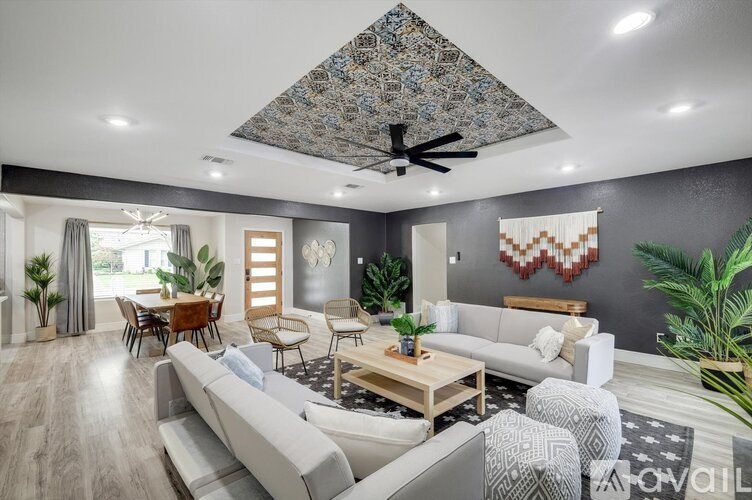 A modern living room with a grey sofa set, wooden coffee table, and a patterned ceiling fan.