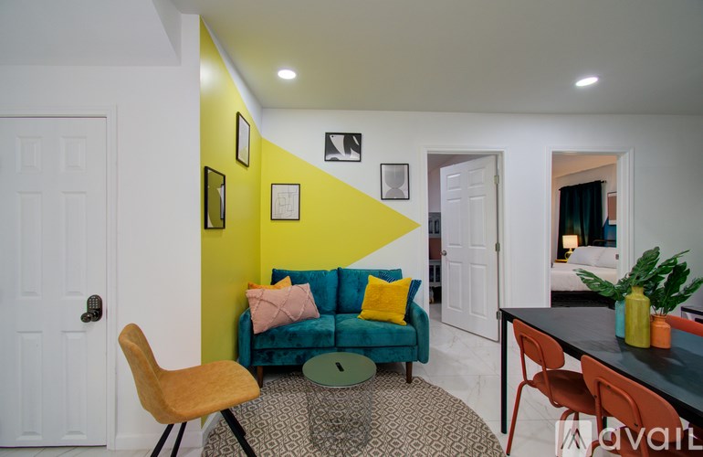 A living room with a blue couch and a yellow wall.