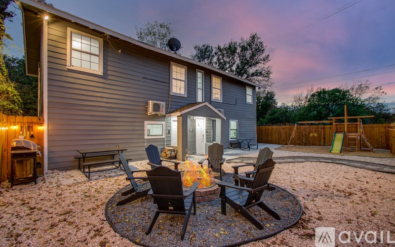 A house with a patio and chairs around a fire pit.
