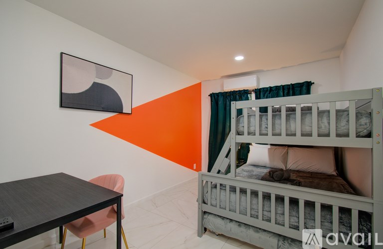 A room with a bunk bed and a table with a chair.